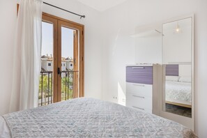 Ein Schlafzimmer mit einem Bett, einem Schminktisch, einem Spiegel und einem Balkon mit Geländer.