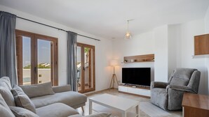 Un salon avec un canapé, un téléviseur, une lampe et un fauteuil.