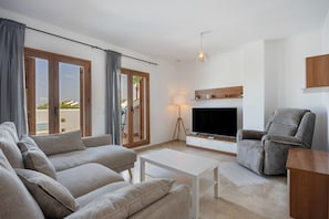 A living room with a sofa, a television, a lamp, and a chair.