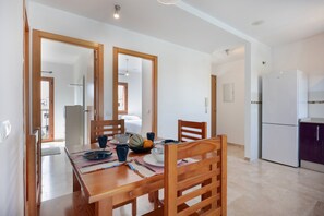 Ein Essbereich mit Holztisch, Stühlen und einer Küche im Hintergrund.