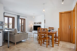 A modern living room with a sofa, dining table, chairs, and a TV.