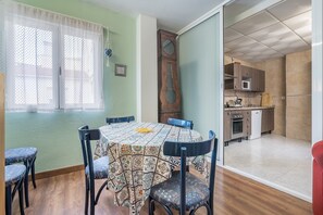 A dining area with a patterned tablecloth, chairs, and a window with a white curtain. - Apartment 'Granada David' with Shared Terrace, Wi-Fi and Air Conditioning (Granada)