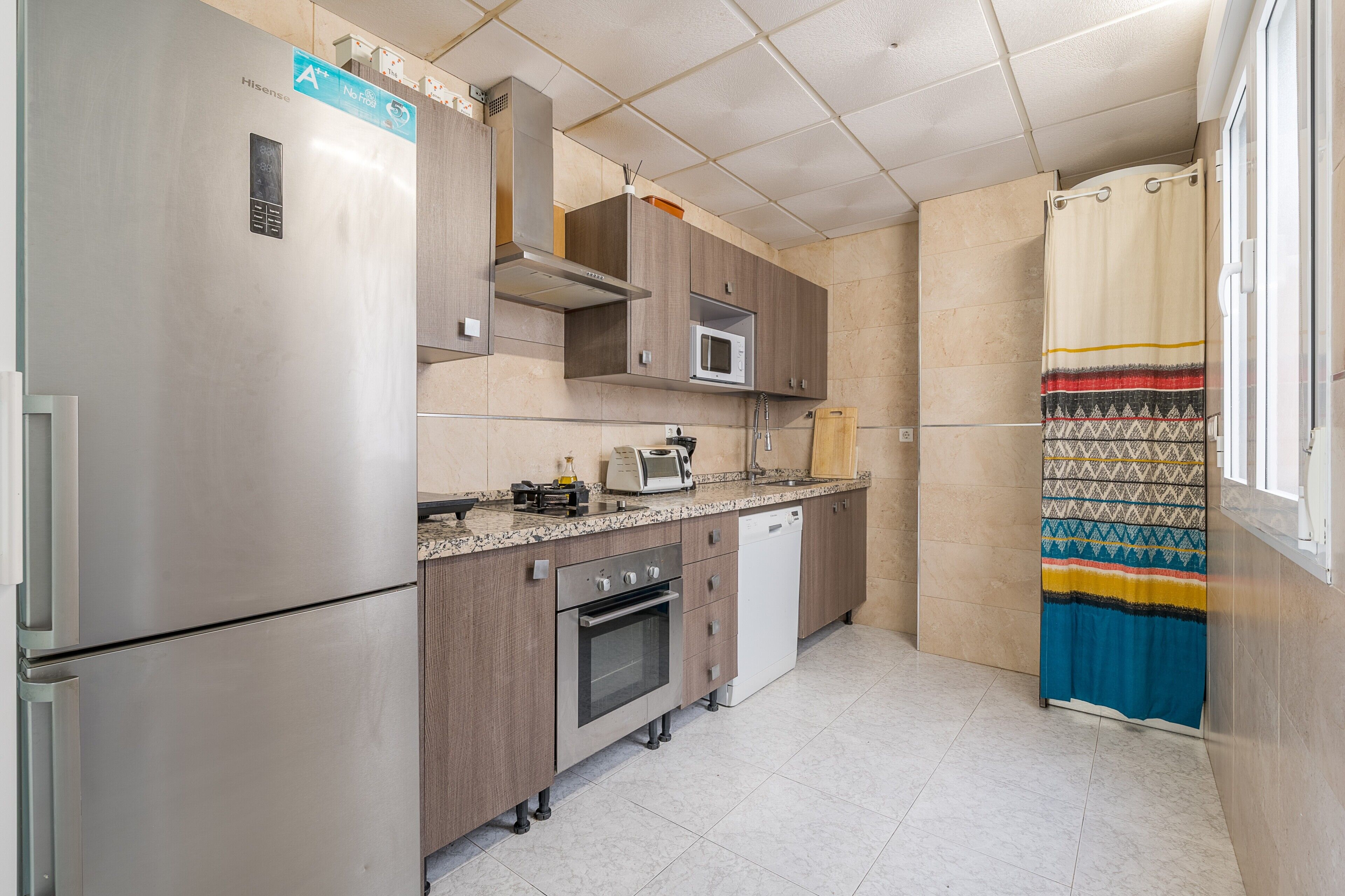 Una cocina compacta con electrodomésticos de acero inoxidable, microondas y lavavajillas.