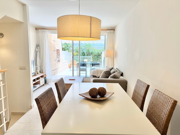 A dining area with a white table, wicker chairs, and a central decorative bowl.