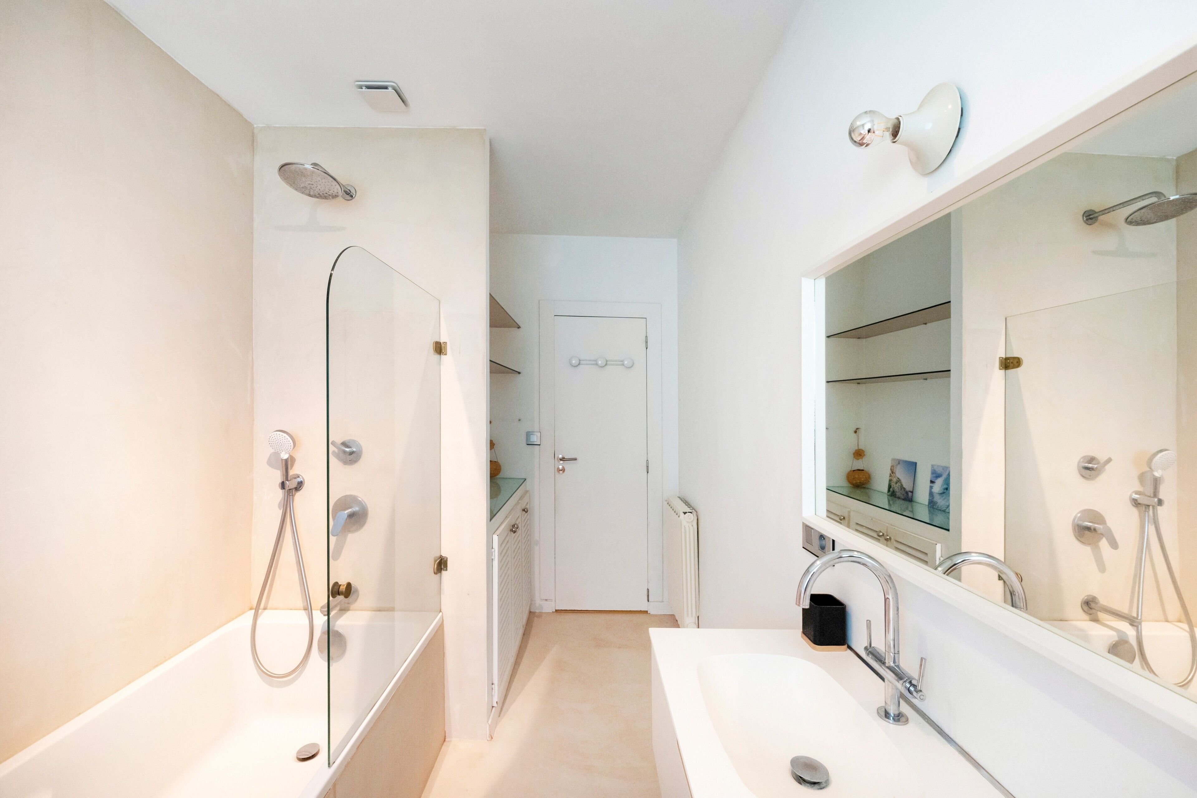 Un baño moderno con cabina de ducha de vidrio, un espejo grande y un lavabo blanco.