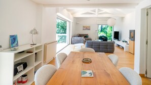 Amplia sala de estar con una mesa de comedor de madera, asientos cómodos, un televisor y vistas al exterior.