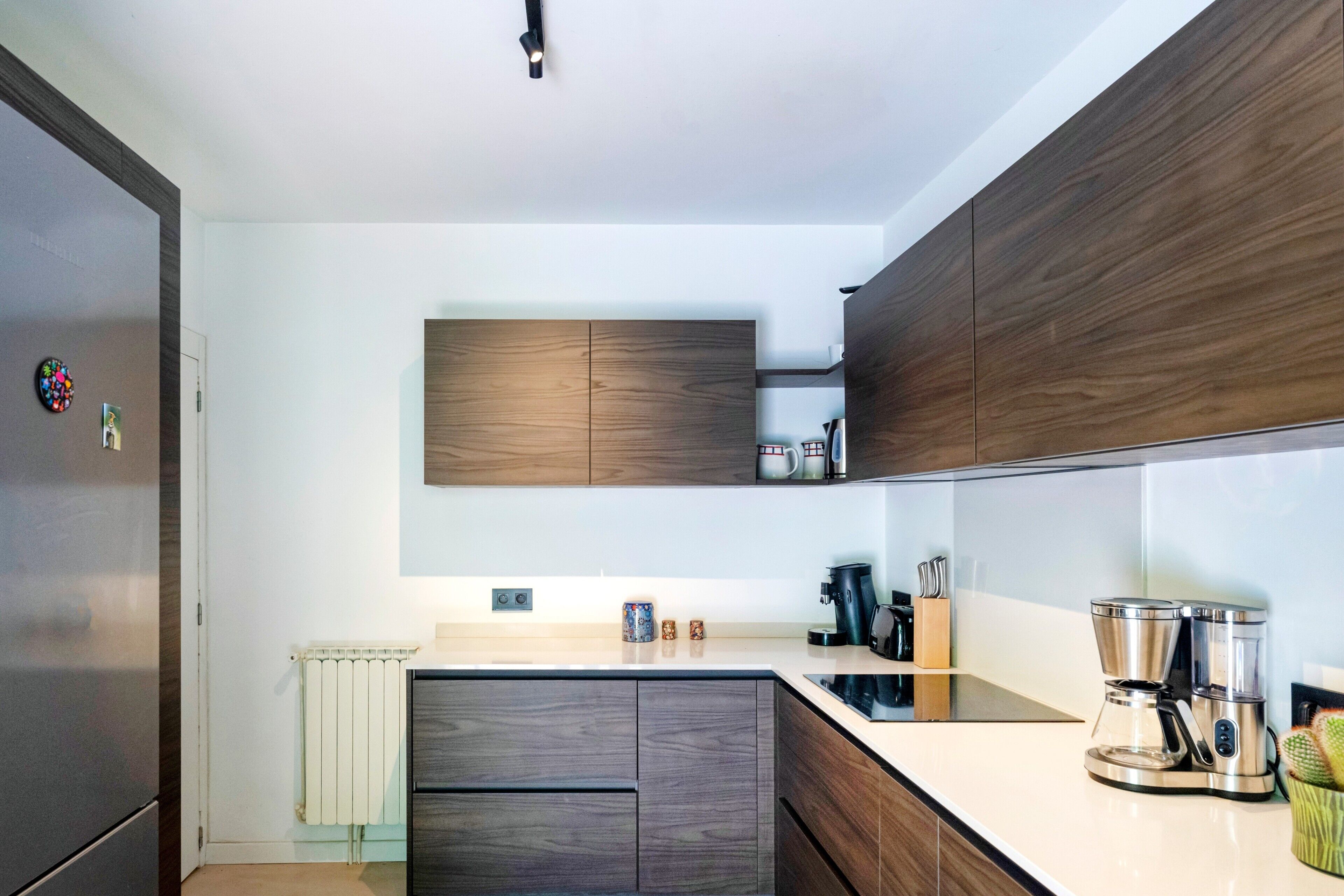 Eine moderne Küche mit Holzschränken, einem eingebauten Herd und einer Kaffeemaschine.