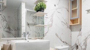 A modern bathroom with a marble backsplash, a rectangular sink, a toilet, and a mirror above the sink. - San Isidro IV - Cozy apartment (Madrid)