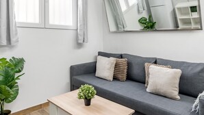 A modern living room with a grey sofa, a wooden coffee table, and a potted plant. - San Isidro IV - Cozy apartment (Madrid)