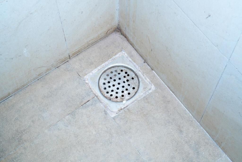 A bathroom with a drain in the corner.