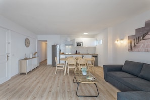 Een moderne woonkamer met een bank, een salontafel en een eethoek met stoelen en een tafel.