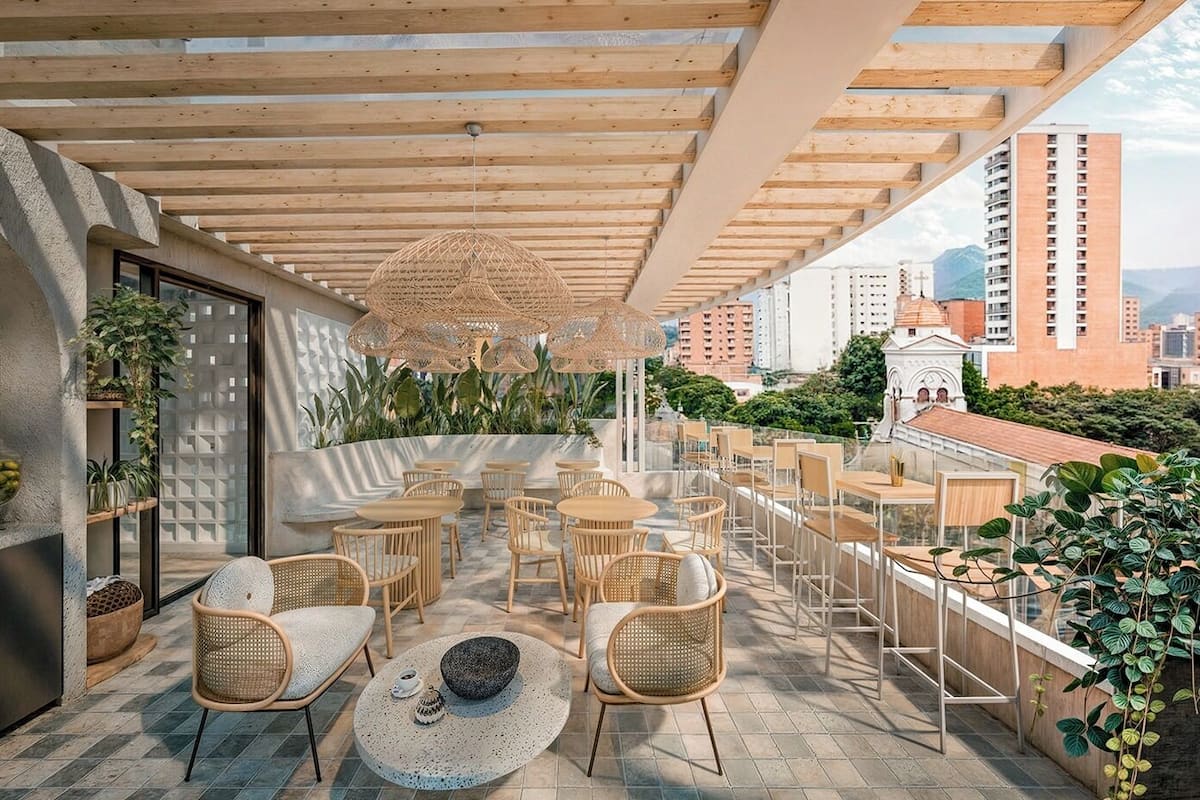 A rooftop terrace with wooden tables and chairs, a buffet area, and a view of the cityscape.