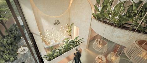 Un hall d’hôtel comprenant un comptoir d’accueil, un espace salon et de nombreuses plantes en pot.