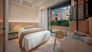 A modern bedroom with a bed, bedside table, chair, and a balcony with a view of buildings. - Hotel Tres Altares Sabaneta (Sabaneta)