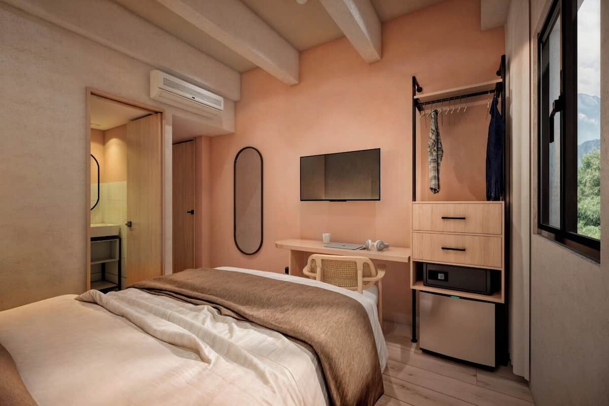 A bedroom with a bed, a desk, a chair, a mirror, and a wardrobe.
