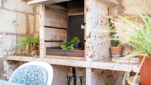 A rustic outdoor seating area with a metal chair, a small window with a shelf, and potted plants. - Holiday Home 'Son Amanada' with courtyard and Wi-Fi (Santa Margalida)
