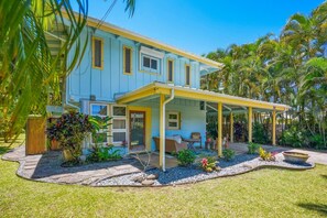 A two-story house with a covered porch, a small garden with tropical plants, and a clear blue sky. - Spacious 5-bedroom house with AC, WiFi in gorgeous Hanalei (Hanalei)