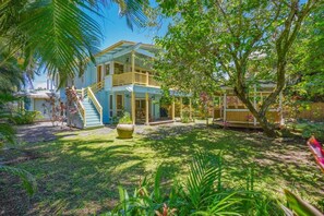 A two-story house with a covered porch, a staircase, and a garden with various plants. - Spacious 5-bedroom house with AC, WiFi in gorgeous Hanalei (Hanalei)