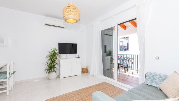 Una sala de estar moderna con sofá, televisor y un amplio ventanal.