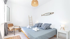 Un dormitorio con cama, mesita de noche, silla y un adorno de pez en la pared.