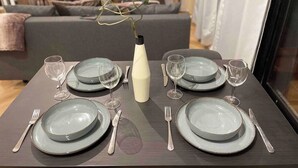 A dining table set with plates, cutlery, and wine glasses, with a vase of flowers in the center. - DG Apartment - Le Relais du Lac, near Disneyland (Lognes)