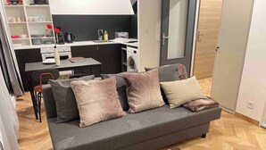 A modern living room with a grey sofa, a coffee table, and a dining area in the background. - DG Apartment - Le Relais du Lac, near Disneyland (Lognes)
