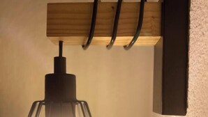 A wall-mounted light fixture with a geometric glass shade and a wooden panel above it. - T2D Apartment - Suite UR near Disneyland Paris (Bussy-Saint-Georges)