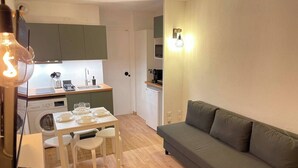 A compact living space with a kitchenette, a dining area with a table and chairs, and a sofa.
