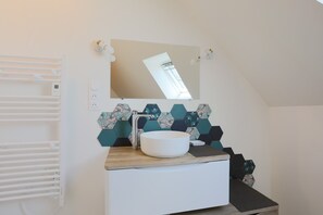Une salle de bain moderne avec un lavabo blanc, un miroir et un porte-serviettes.