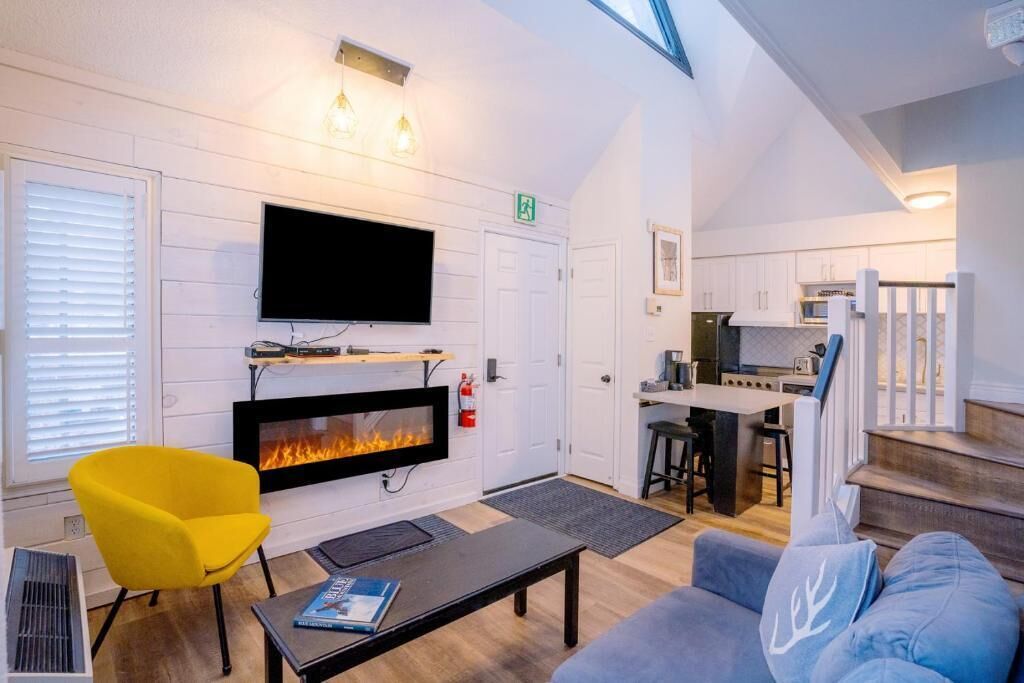 A cozy living area with a fireplace, a flat-screen TV, and a bright yellow chair.