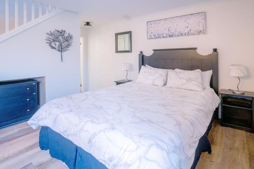 Une chambre à coucher comprenant un lit, des tables de chevet, une œuvre d’art murale et une feuille décorative accrochée au mur.