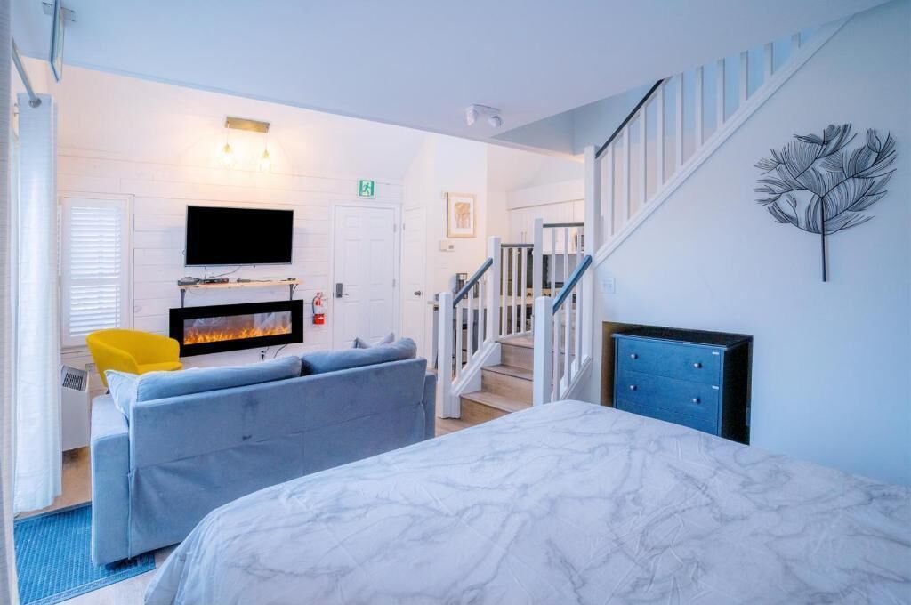 Une chambre d’hôtel avec un lit, un canapé, une télévision et une cheminée.