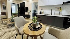 Un salon moderne avec un canapé, une table basse et une petite table en bois sur laquelle est posée une plante.
