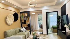 Un salon moderne avec un canapé, une table basse et une bibliothèque. Il y a un balcon avec vue sur l’extérieur.