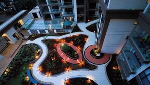 Un bâtiment moderne doté d’une cour aménagée avec des allées sinueuses et des espaces verts circulaires.