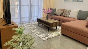 Un salon moderne avec un canapé, une table basse et un téléviseur posé sur un meuble en bois.