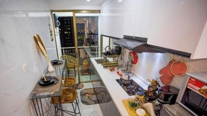 A modern kitchen with a glass dining area, stainless steel appliances, and a view of the cityscape. - Kilimani One bedroom (Nairobi)