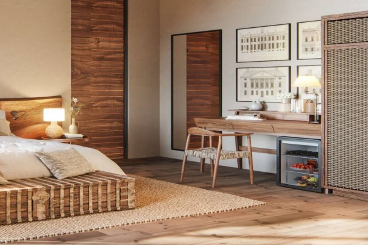 A bedroom with a wooden headboard, a bed with white linens, a woven bench, a desk with chairs, and framed pictures on the wall.