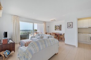 A modern hotel room with a sofa, a dining area, and a kitchen. - Apartment 'Infinity View Menorca' with Sea View, Shared Pool and Private Terrace (Es Mercadal)