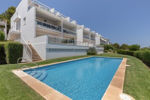 A modern building with a swimming pool, balconies, and a clear sky. - Apartment 'Infinity View Menorca' with Sea View, Shared Pool and Private Terrace (Es Mercadal)