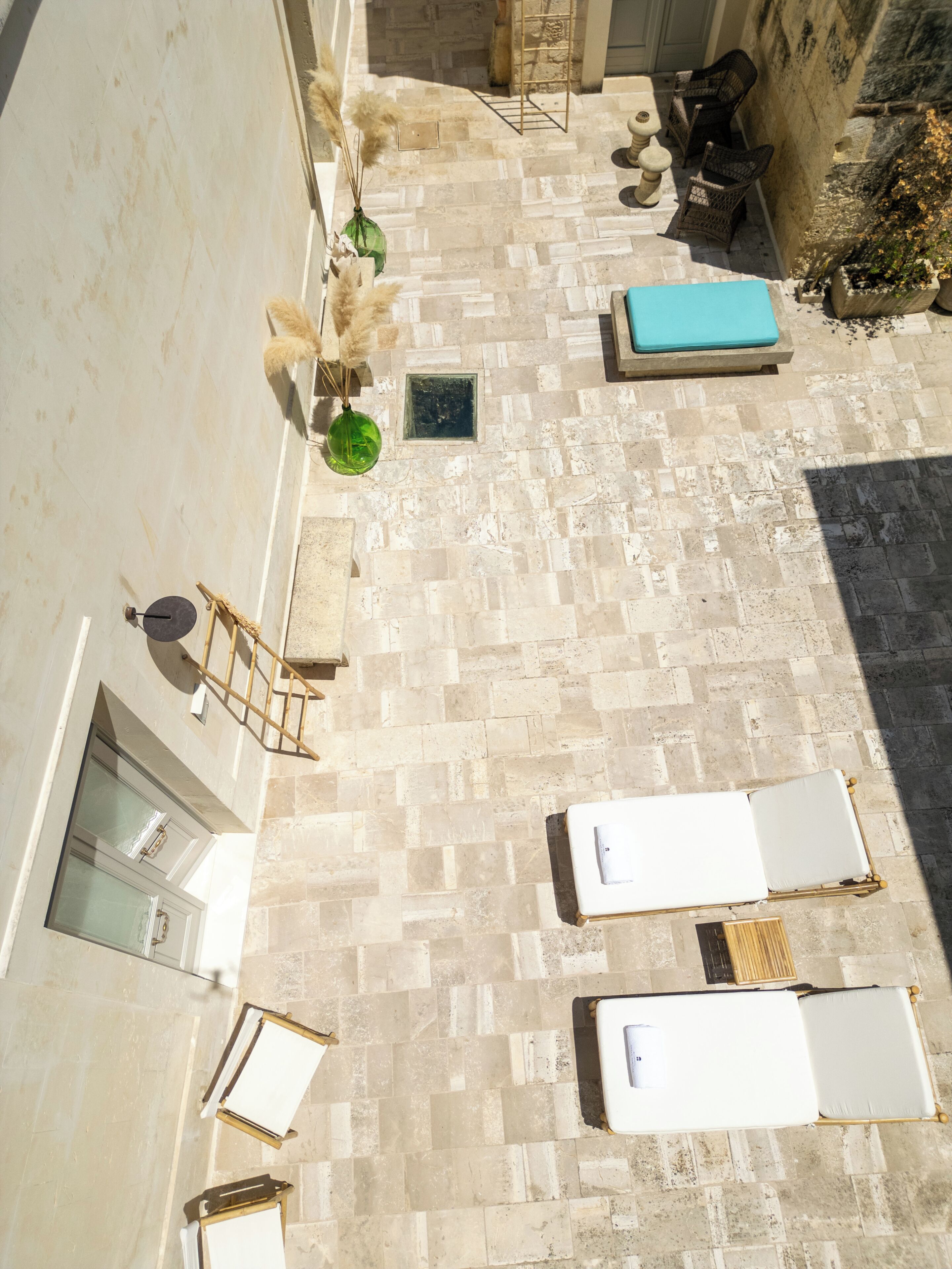 Eine Dachterrasse mit Steinboden, Liegestühlen, einem kleinen Tisch und einem Blumentopf.