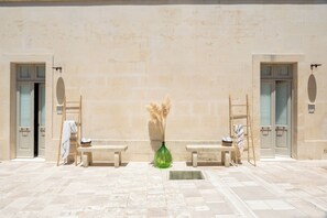 A building facade with two doors, a bench, a ladder, and a vase with pampas grass. - Borgo delle Dimore Suites (Maglie)