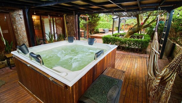 A hot tub with a wooden deck, surrounded by greenery and a covered area with a bench. - Spectacular Villa only 20min from Bogota - Cota Cundinamarca (Vereda el Abra)