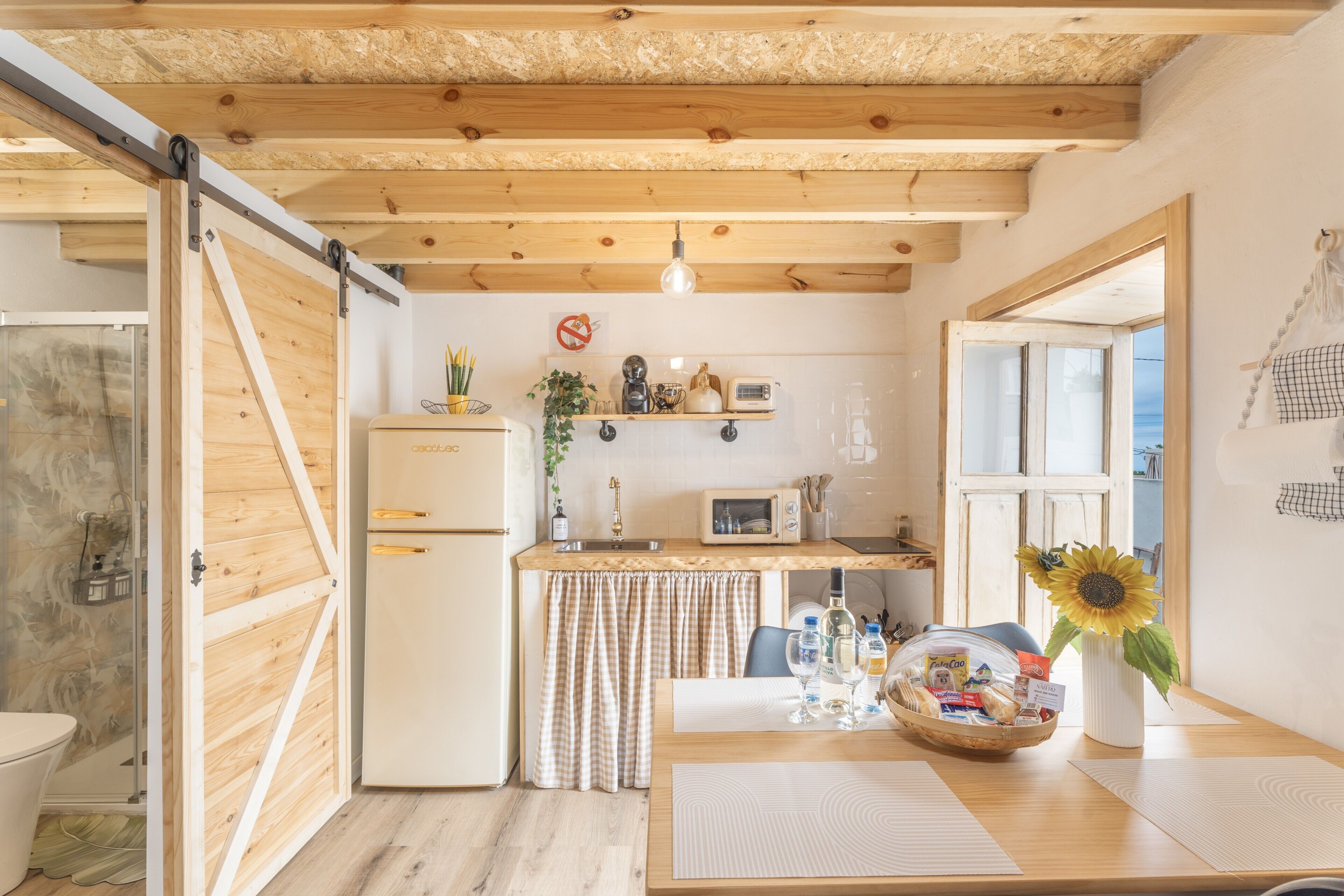 Une cuisine de taille réduite avec un plafond en bois, un réfrigérateur, un four à micro-ondes et un évier.