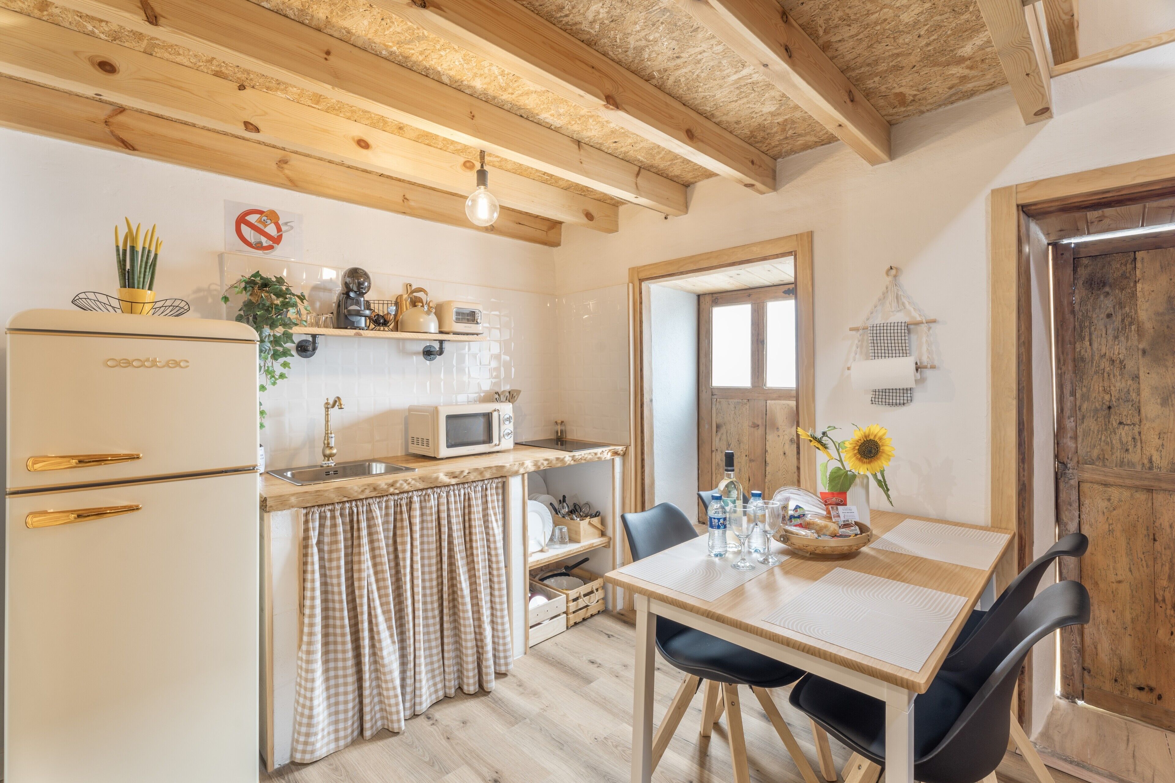 Una cocina con refrigerador, microondas y vigas de madera en el techo.