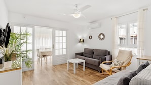 A spacious living area with a sofa, armchair, and coffee table, a dining area with chairs and a table, and a ceiling fan. - Apartment 'Fuengirola Beach' with Sea View, Wi-Fi and Air Conditioning (FUENGIROLA)