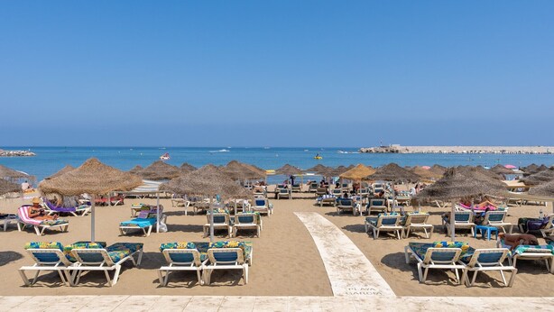 A beach with rows of sun loungers and thatched umbrellas, a clear blue sky, and the sea in the background. - Apartment 'Fuengirola Beach' with Sea View, Wi-Fi and Air Conditioning (FUENGIROLA)