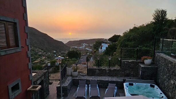 Una terraza en la azotea con sillones de descanso, un jacuzzi y una vista espectacular al atardecer.