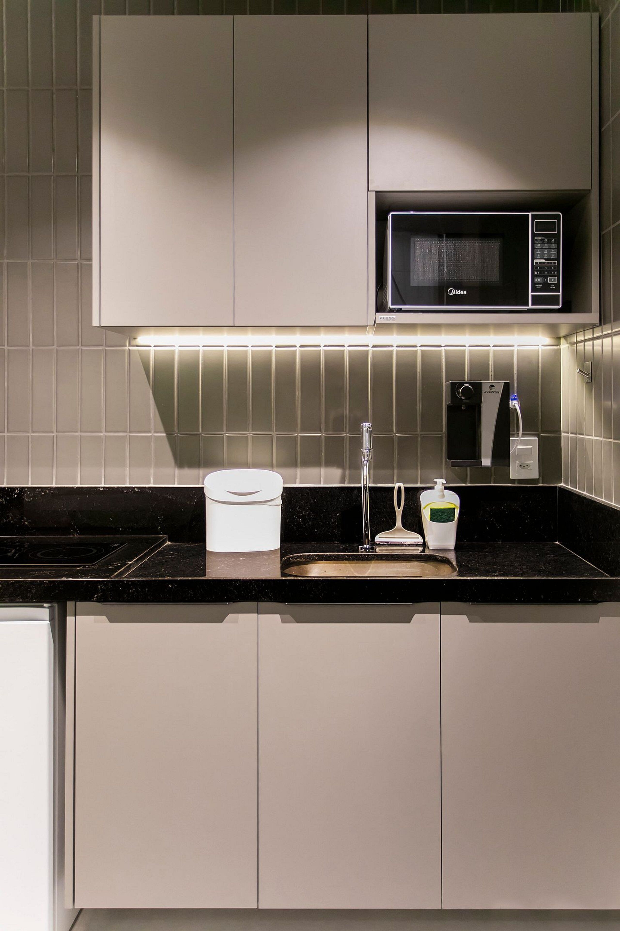 A modern kitchen with a built-in microwave, a sink, and a soap dispenser.