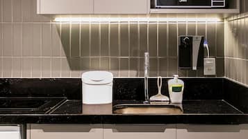 A modern kitchen with a built-in microwave, a sink, and a soap dispenser.